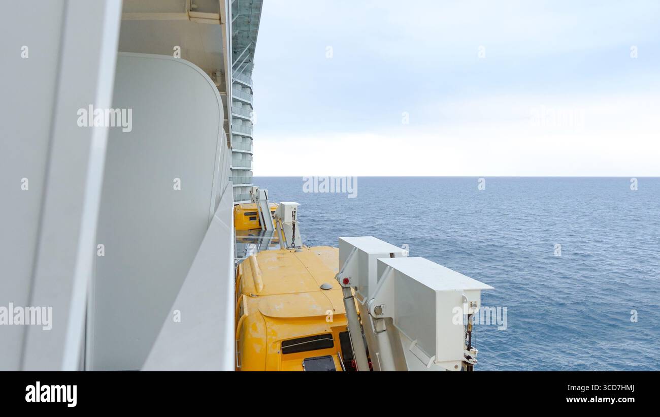 La vista sul ponte della nave presenta macchinari gialli che si affacciano sull'oceano calmo e sul cielo nuvoloso con ampio spazio per copiare il testo Foto Stock