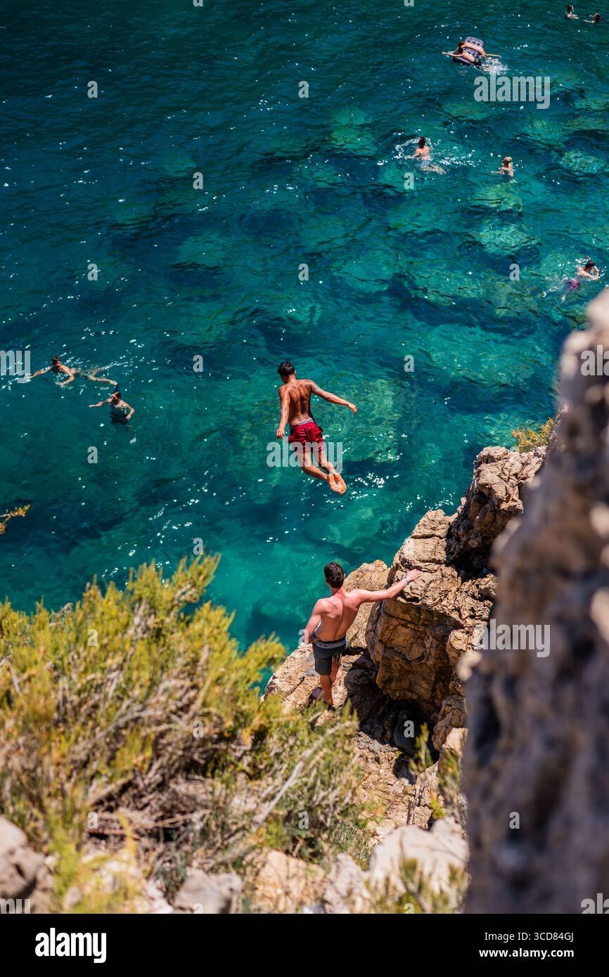 Persone che nuotano e saltano in mare da Pendma Chiatt (pietra piana), Polignano a Mare, Puglia, Italia Foto Stock