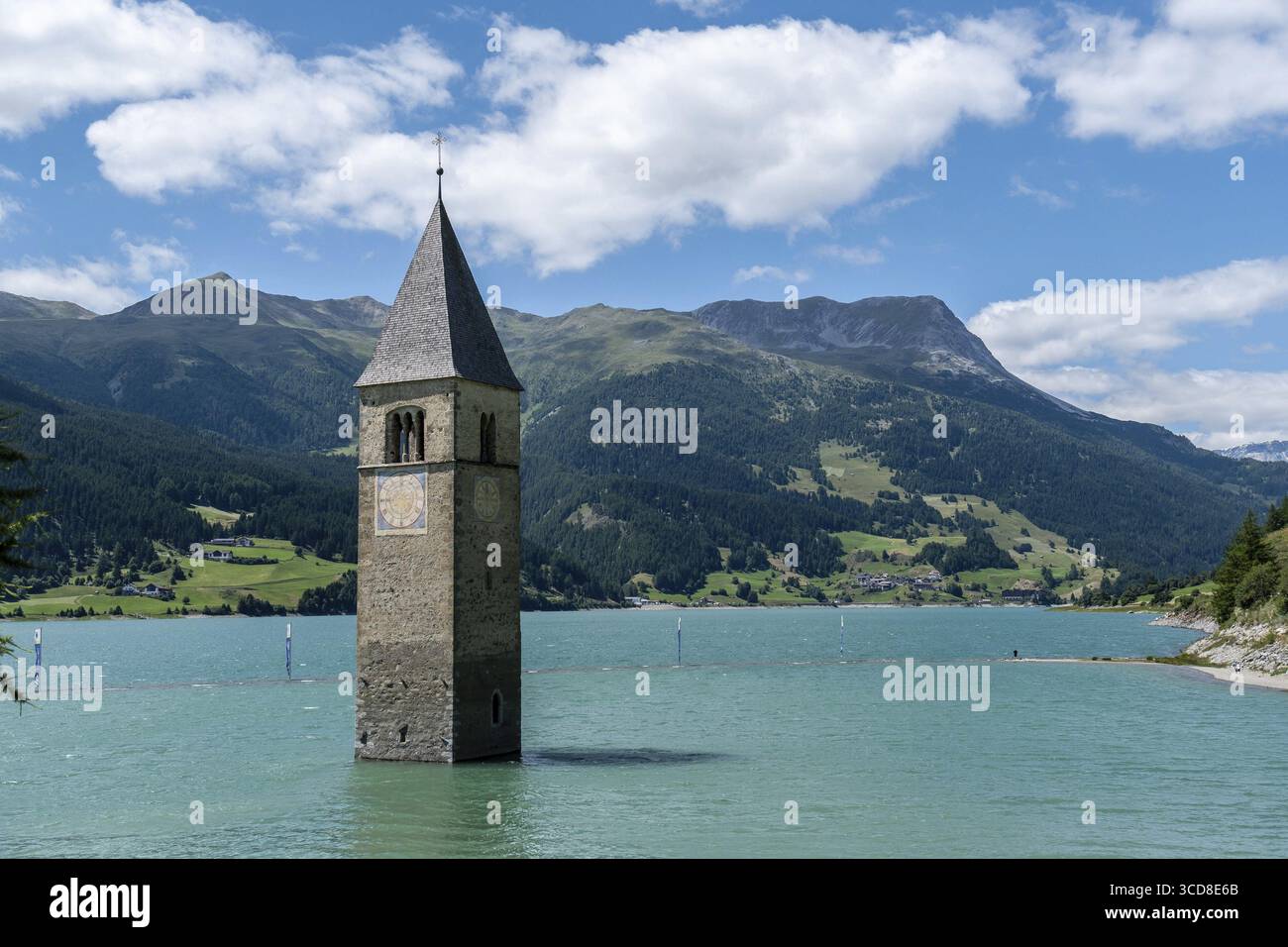 La torre della chiesa sommersa nel lago di Resia sullo sfondo alpino Foto Stock