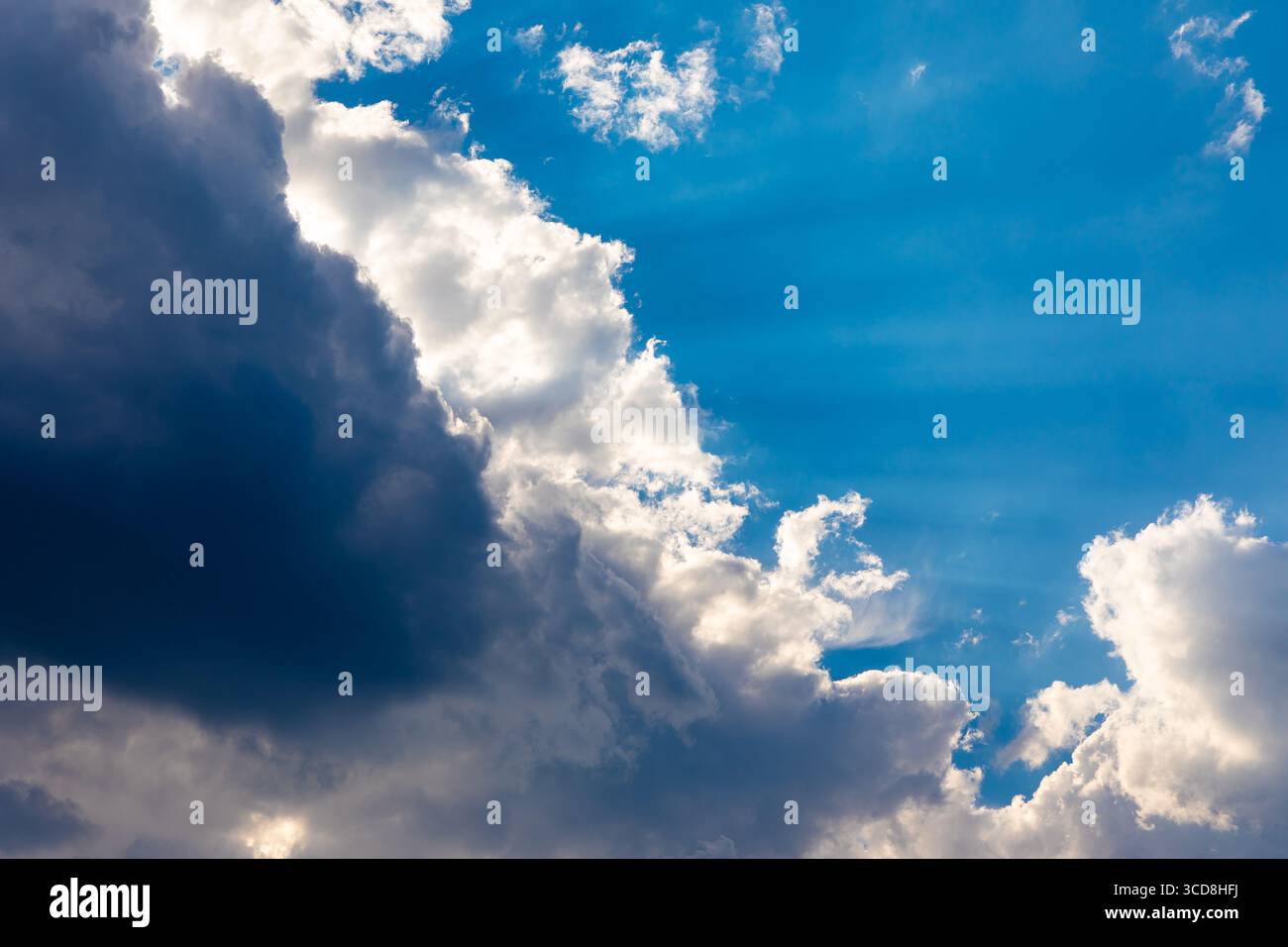 Cielo blu brillante con spettacolari nuvole illuminate dal sole, che creano un contrasto dinamico ideale per sfondi, temi naturali e progetti di design creativo. Foto Stock