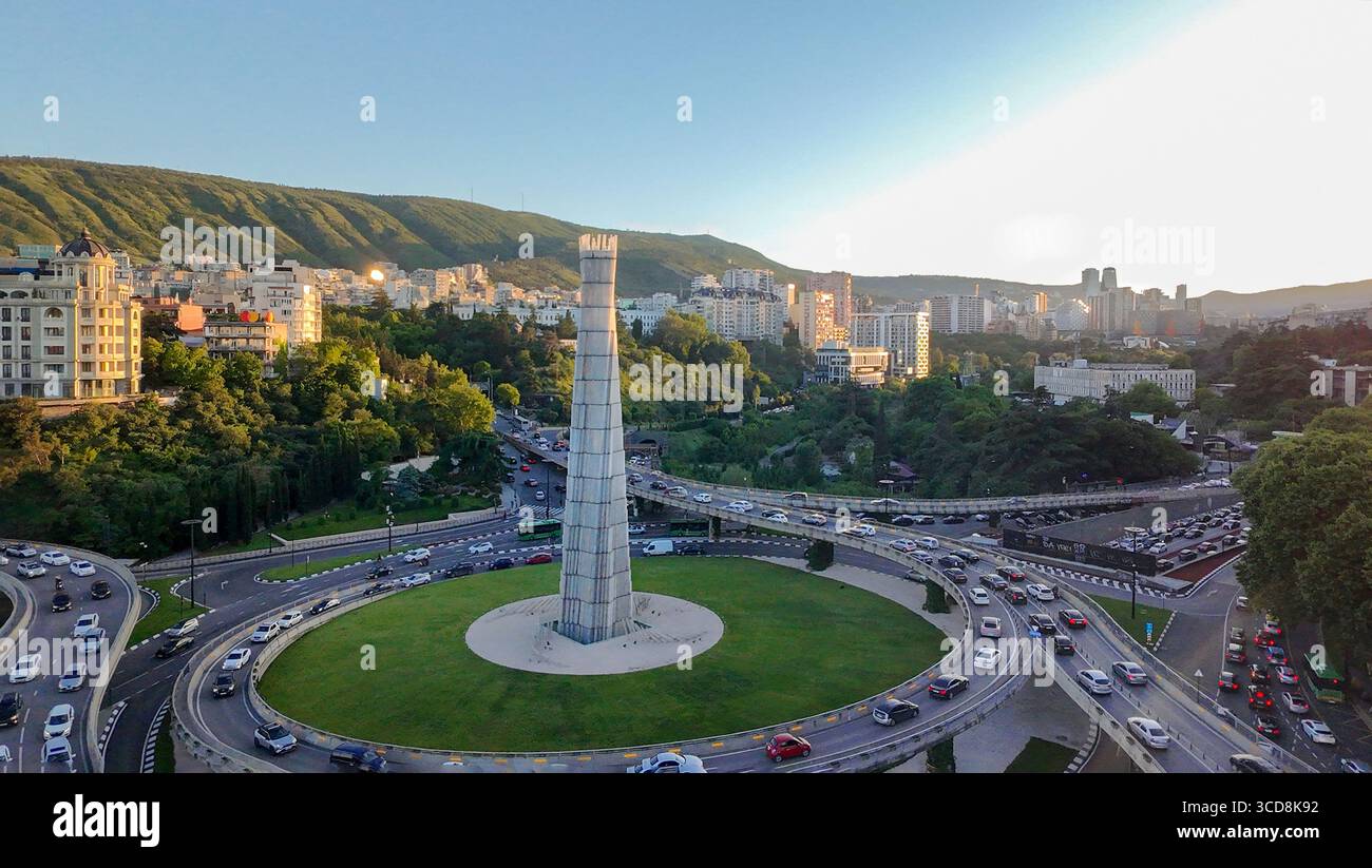 05-16-2025 TBILISI GEO punto di vista del drone complesso moderno incrocio stradale della Piazza degli Eroi e del Monumento degli Eroi al tramonto a Tbilisi Foto Stock