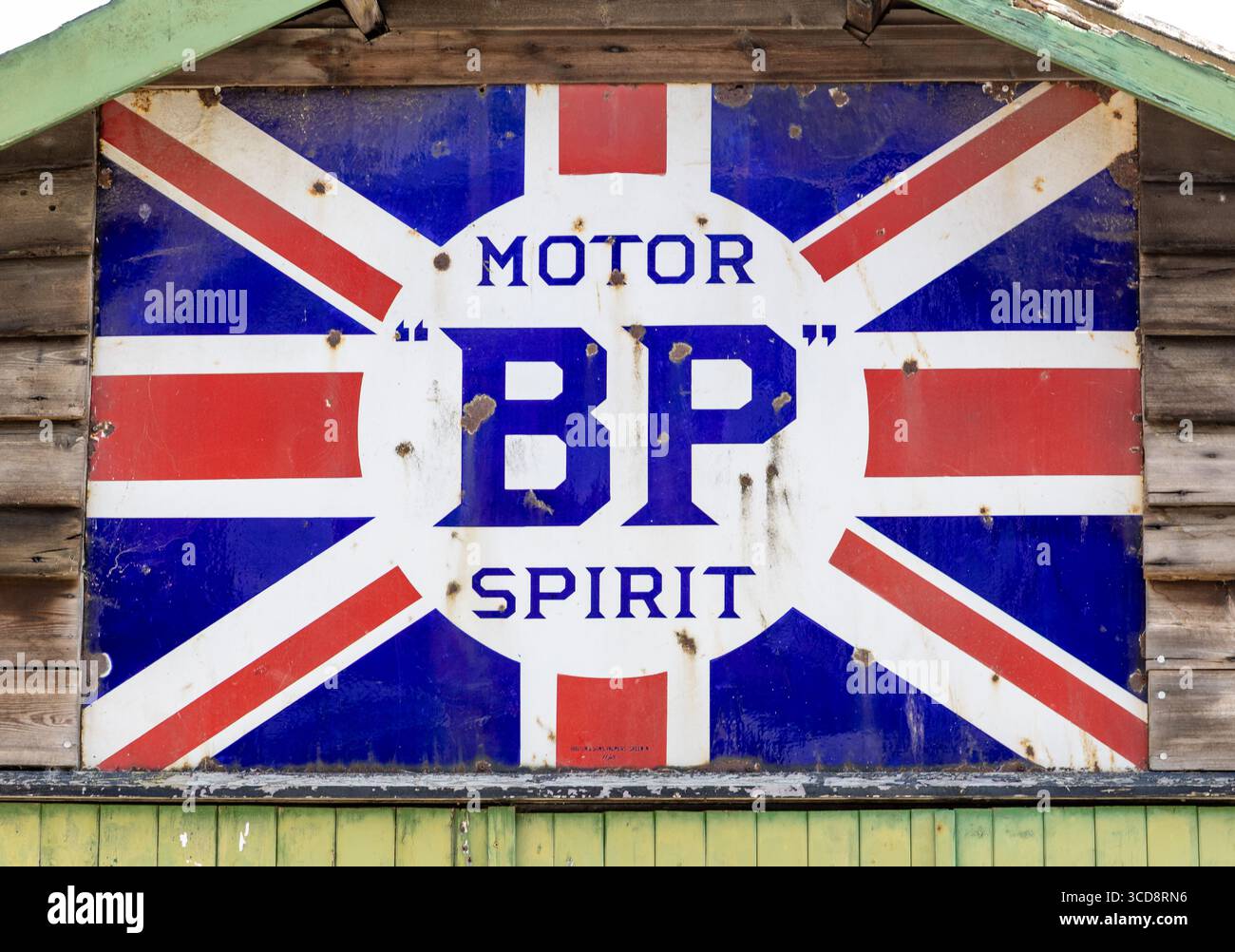 Insegna vintage BP Motor Spirit con un design Union Jack arrugginito esposto su un muro di legno Foto Stock