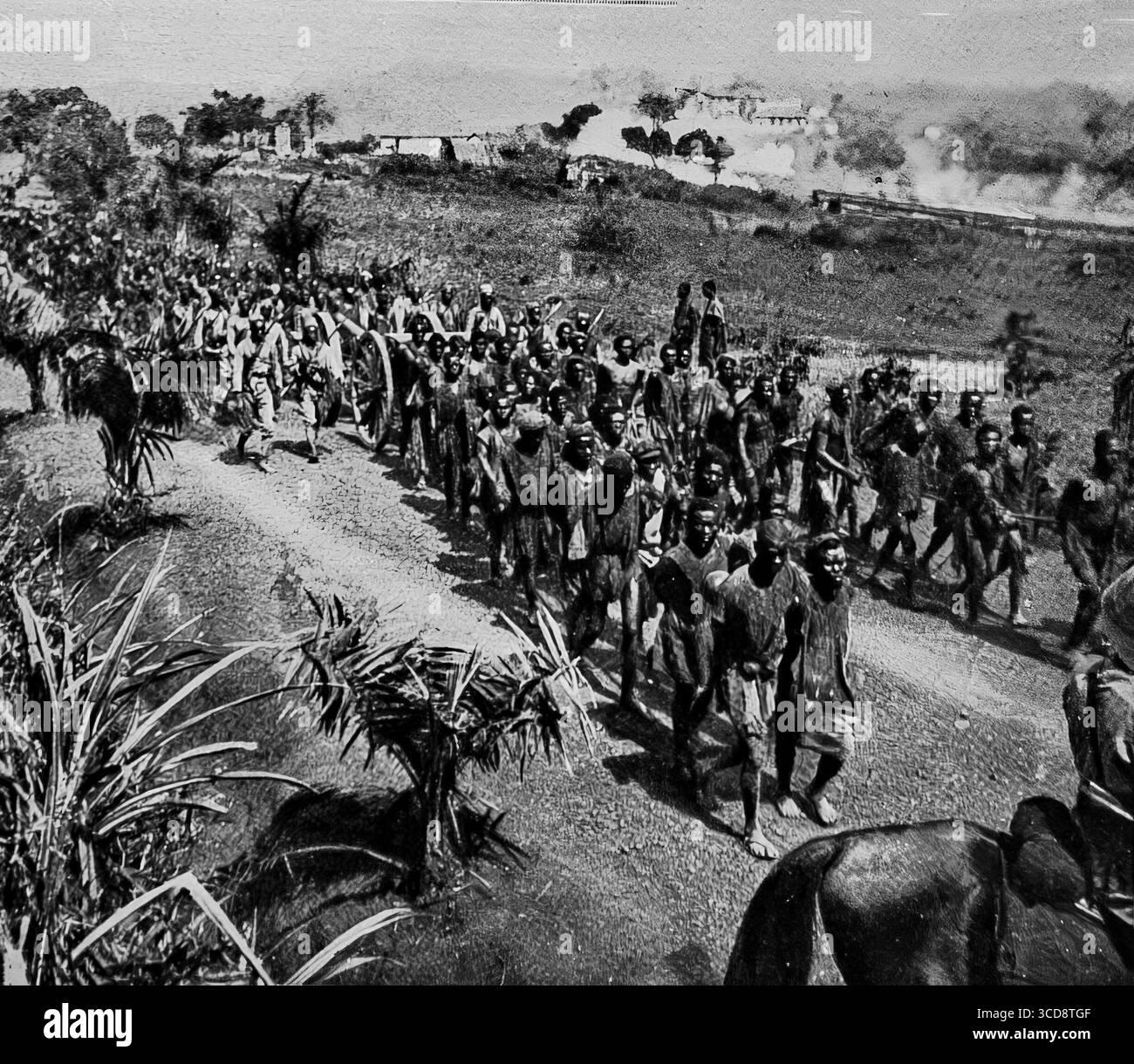 Aprile 1916 l'illustrazione fotografia dell'esercito coloniale francese che entra a Yaoundé, Camerun, durante la prima guerra mondiale. Il cannone da campo da 95 mm, trainato da 150 portatori africani, arriva in città mentre il fumo sale dai sobborghi in fiamme. Questa decisiva avanzata segnò il crollo della resistenza tedesca e il successo della campagna alleata dell'Africa occidentale, un raro momento documentato della grande Guerra nel teatro africano. Foto Stock