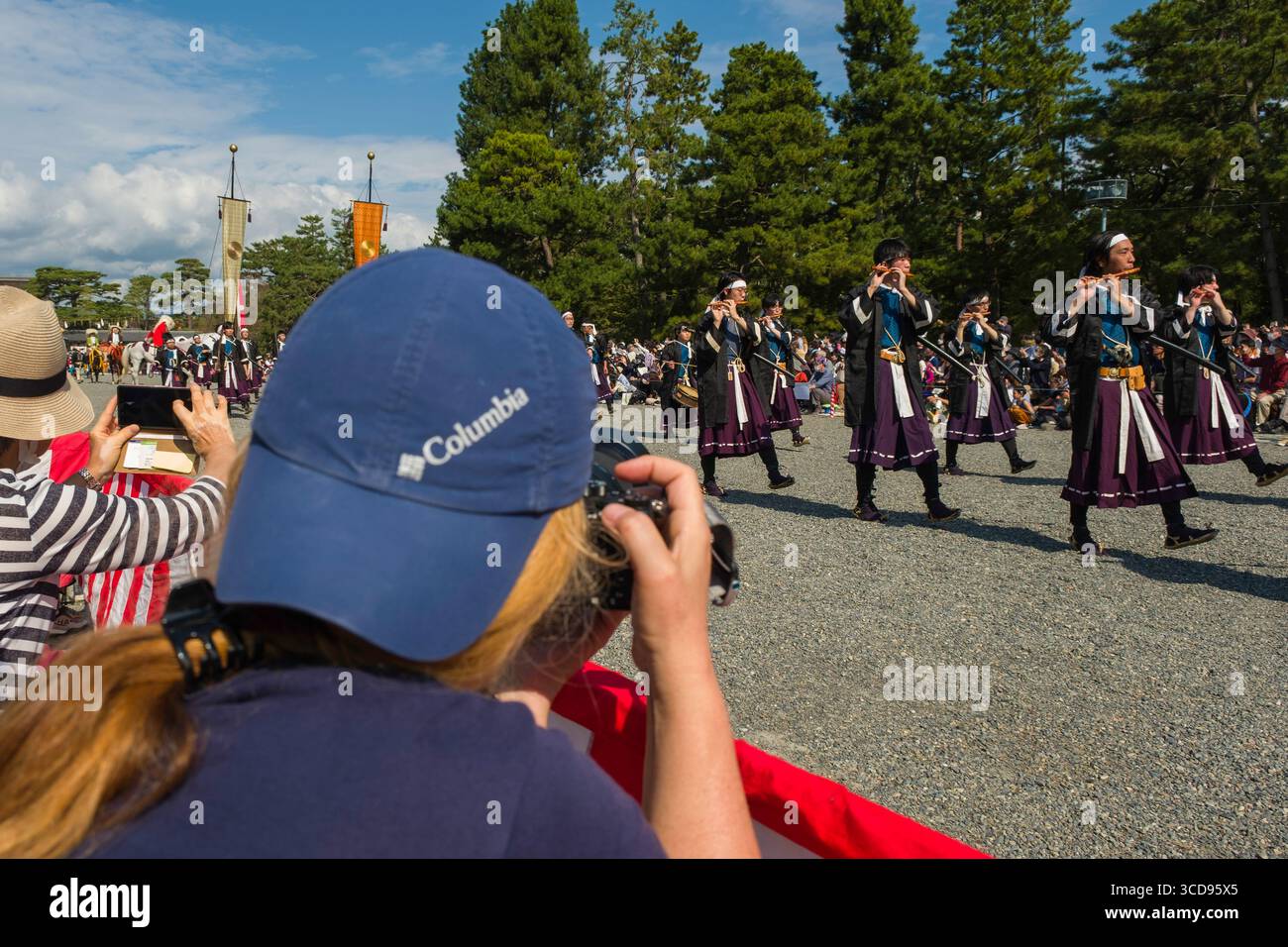 Parte posteriore di una fotografa che fotografa la processione dei saldi Meiji Restoration dell'Esercito Imperiale che marciano mentre suonano flauti fischietti durante il Jidai Foto Stock