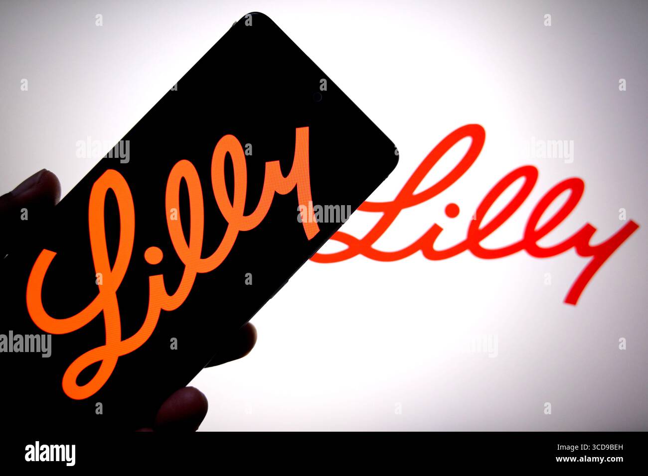 In questa illustrazione fotografica, un logo Eli Lilly viene visualizzato su uno smartphone e sullo sfondo. Foto Stock
