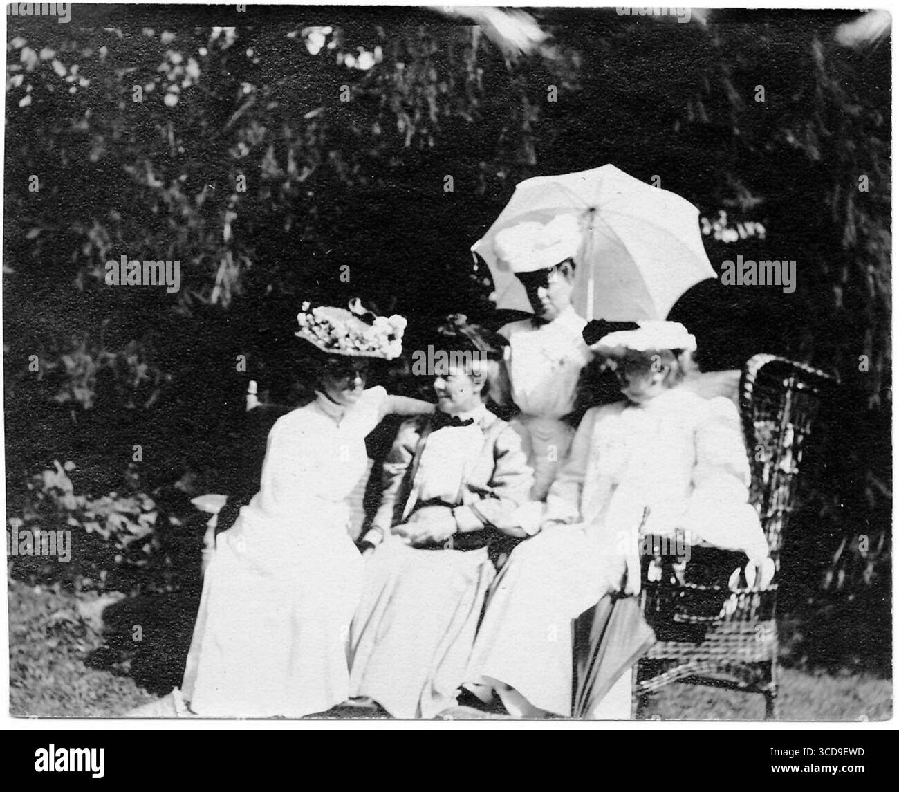 Quattro donne posano all'aperto, tre sedute e un ombrellone in piedi. Tutti indossano abiti e cappelli bianchi. Ritratto di gruppo di Miss Crosby, Fanny Stone, Mary King Longfellow e Alice Longfellow in un giardino, probabilmente al 113 di Brattle Street, Cambridge. Circa 1900-1910. Inciso sul verso in matita in corsivo di H.W.L. Dana: 'Miss Crosby, Miss Stone, Mamie Longfellow. Alice M. Longfellow. Foto Stock