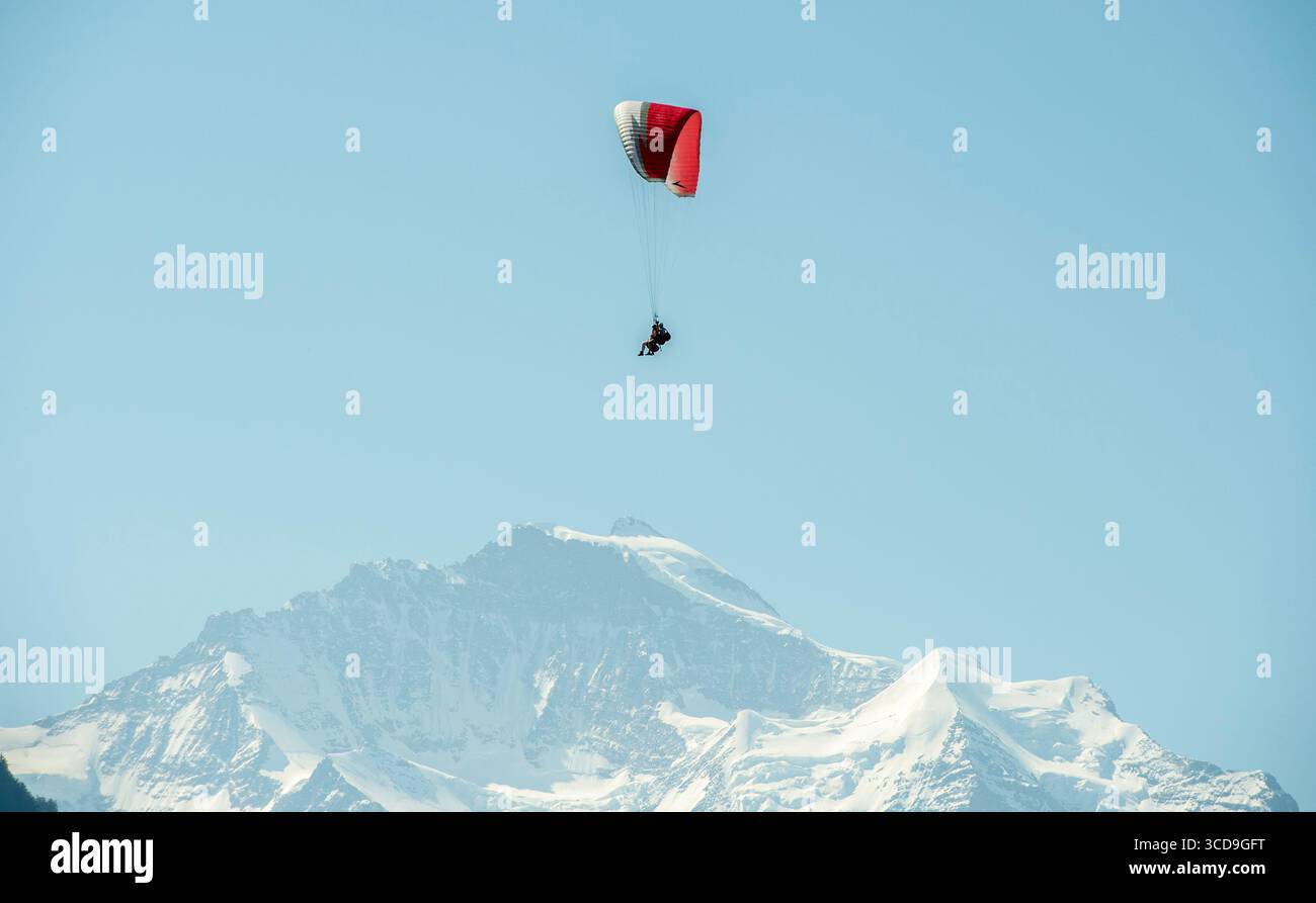 Parapendio che sorvola la vetta innevata della montagna con cielo azzurro, sport estremi, paesaggio suggestivo dell'Himalaya, esplorazione del viaggio Foto Stock