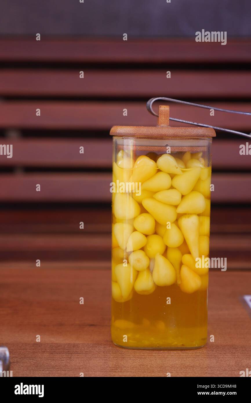 Frutta gialla conservata in vaso di vetro con coperchio in legno Foto Stock
