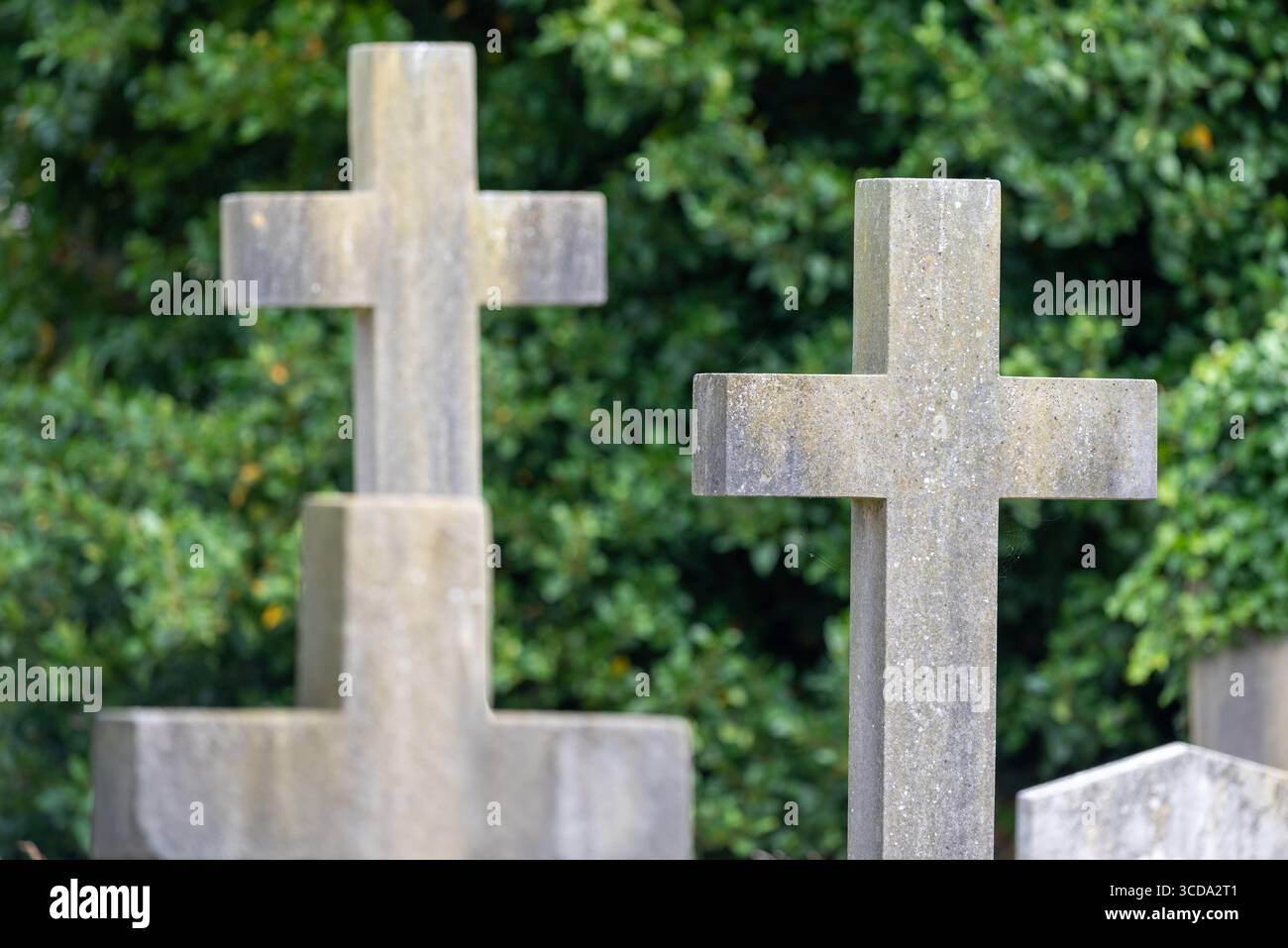 Pietre tombali incrociate in un cimitero, con l'attenzione su una e le altre fuori fuoco. Foto Stock