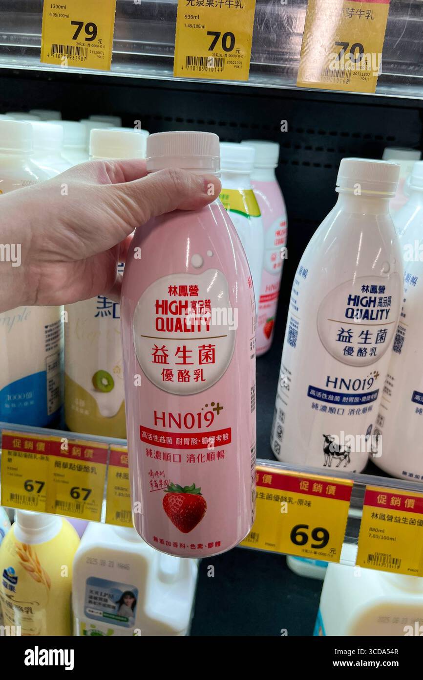 Una mano che tiene una bevanda allo yogurt davanti a un'esposizione di prodotti per bevande presso un supermercato. Foto Stock