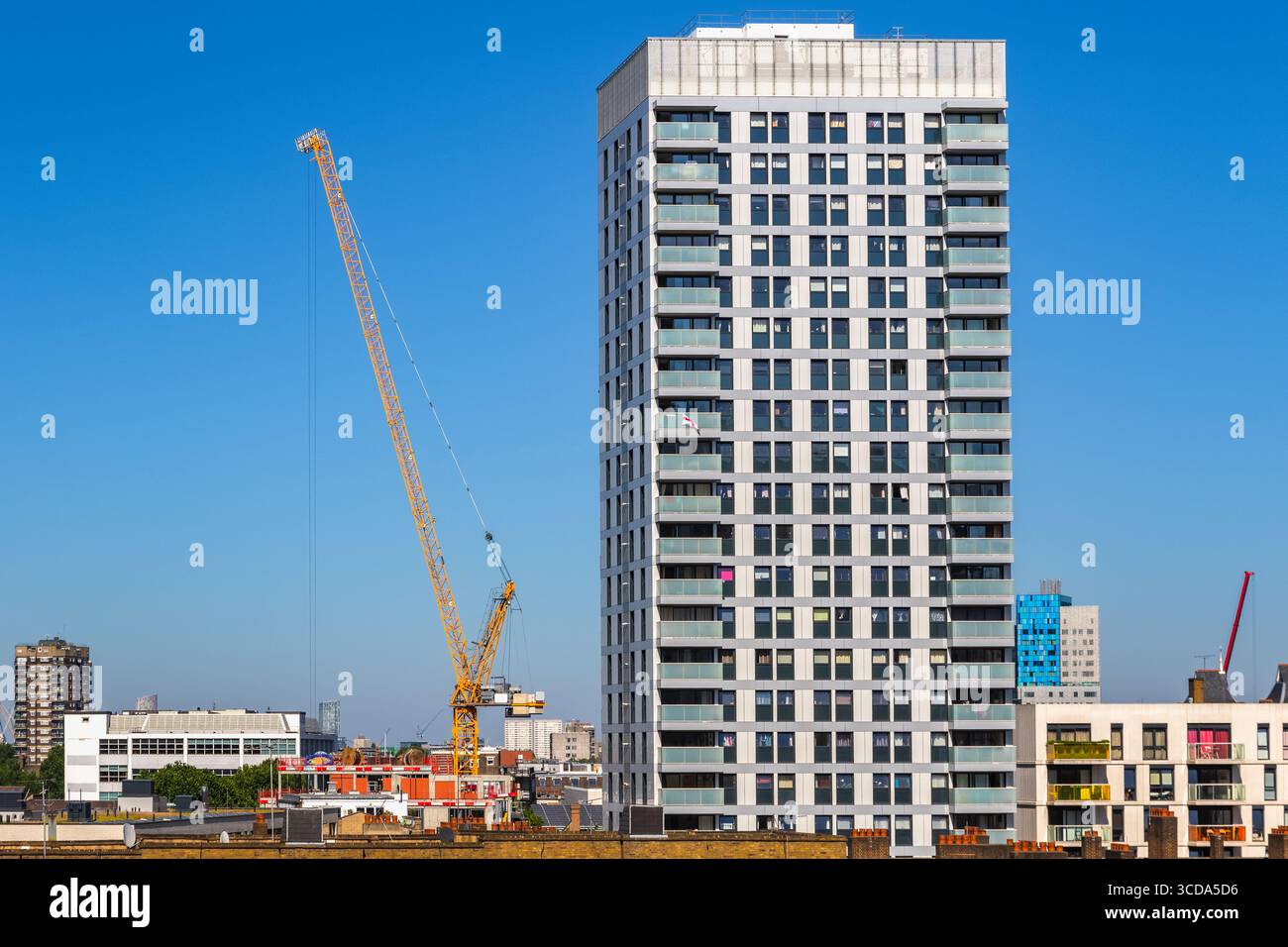 Edificio a torre di nuova costruzione residenziale con una gru a Londra contro un cielo senza nuvole Foto Stock