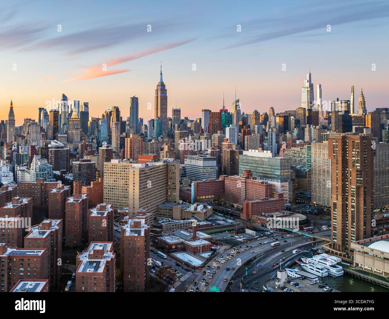 Vista aerea dello skyline con l'Empire State Building che pierta il cielo, un arazzo di cemento e vetro che cattura le calde sfumature del sole che tramonta, New York, New York, Stati Uniti. Foto Stock