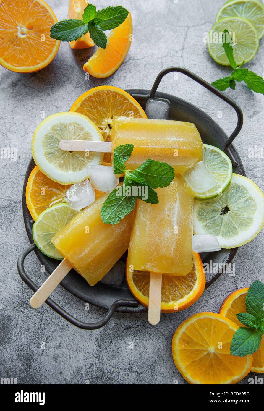 Pop-cicle di frutta e arancia, cubetti di ghiaccio e fette di agrumi. Foto Stock