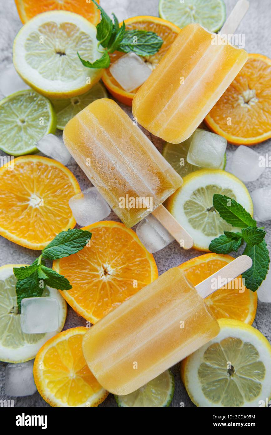 Pop-cicle di frutta e arancia, cubetti di ghiaccio e fette di agrumi. Foto Stock