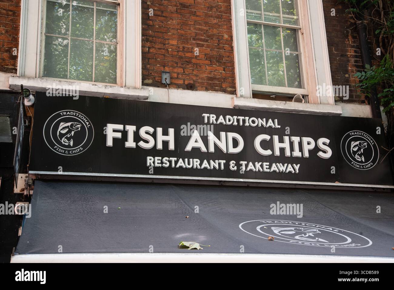 Fai shopping sul cartello con la scritta "Traditional Fish and Chips - Restaurant and Takeaway", che promuove la classica cucina britannica in un ambiente informale. Foto Stock