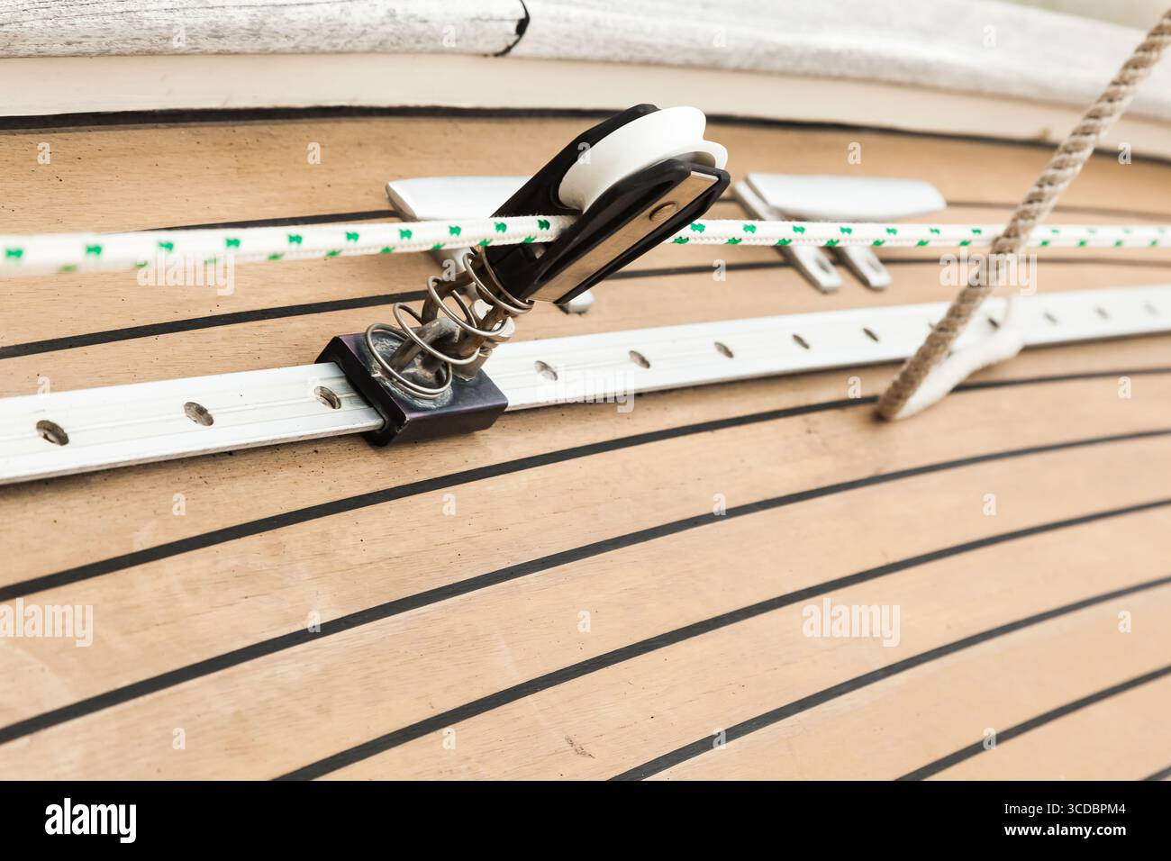 Parte del ponte in teak di uno yacht a vela con elementi di fissaggio per il fissaggio delle funi. Foto Stock