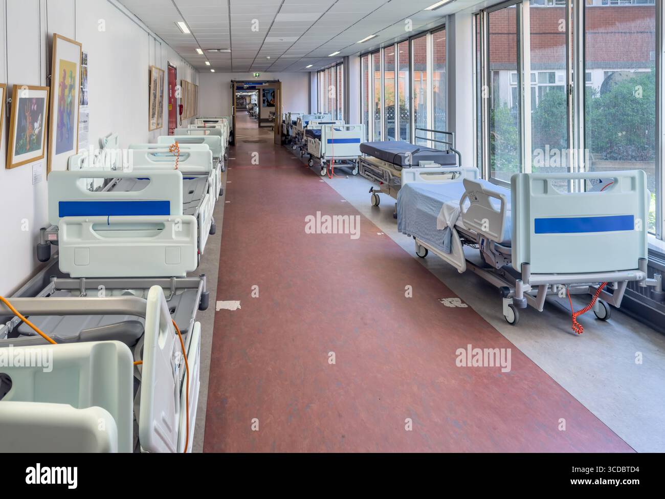 Letti vuoti allineati in un corridoio ospedaliero abbandonato. Foto Stock