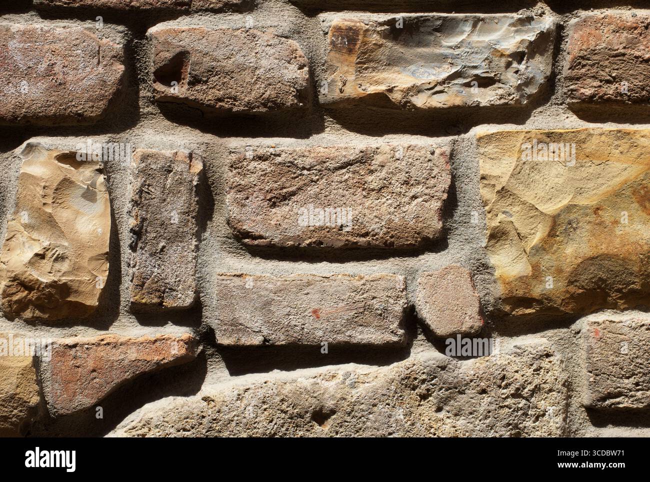 Pietra rustica, pareti in mattoni con superficie ruvida ruvida, dettagli di costruzione in muratura storica, roccia naturale, mattoni invecchiati utilizzati nell'architettura tradizionale. Foto Stock