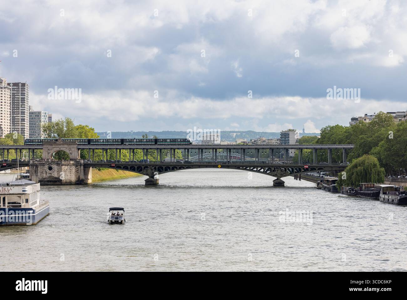 Vista di un treno che attraversa il Pont de Bir-Hakeim, che attraversa la Senna con barche che navigano sotto, sullo sfondo di edifici parigini, Parigi, Île-de-France, Francia. Foto Stock