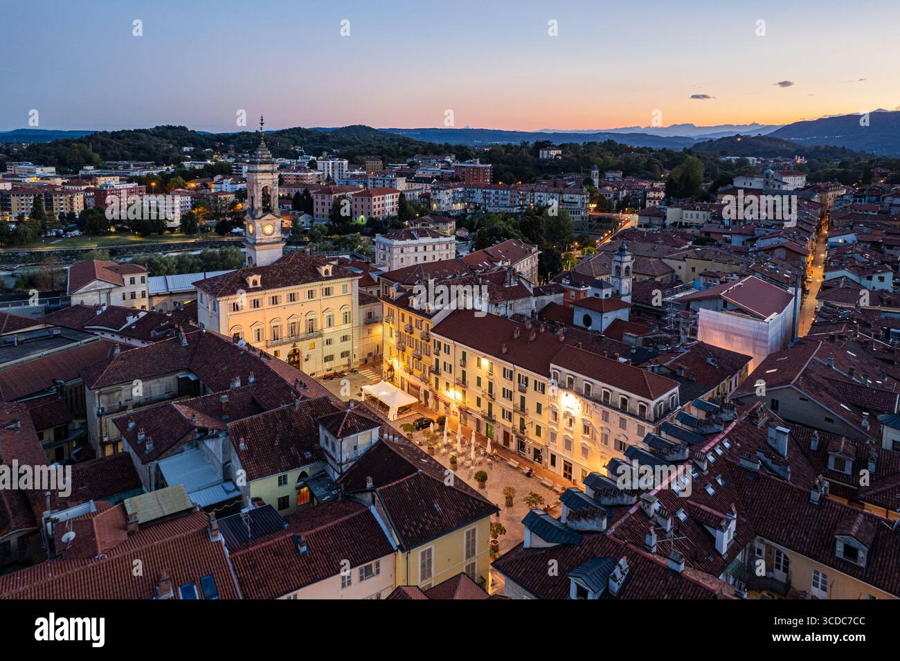Vista aerea delle luci calde che illuminano gli edifici storici e il Duomo di Ivrea, in contrasto con il cielo che svanisce al crepuscolo, Ivrea, Piemonte, Italia. Foto Stock