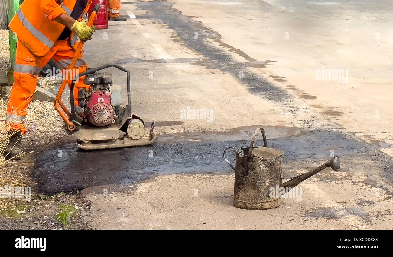 Winchester, Hampshire, Inghilterra, Regno Unito. 07.08.2025. Workman utilizza un compattatore per terminare la posa dell'asfalto dopo l'installazione di una nuova rete interamente in fibra Foto Stock