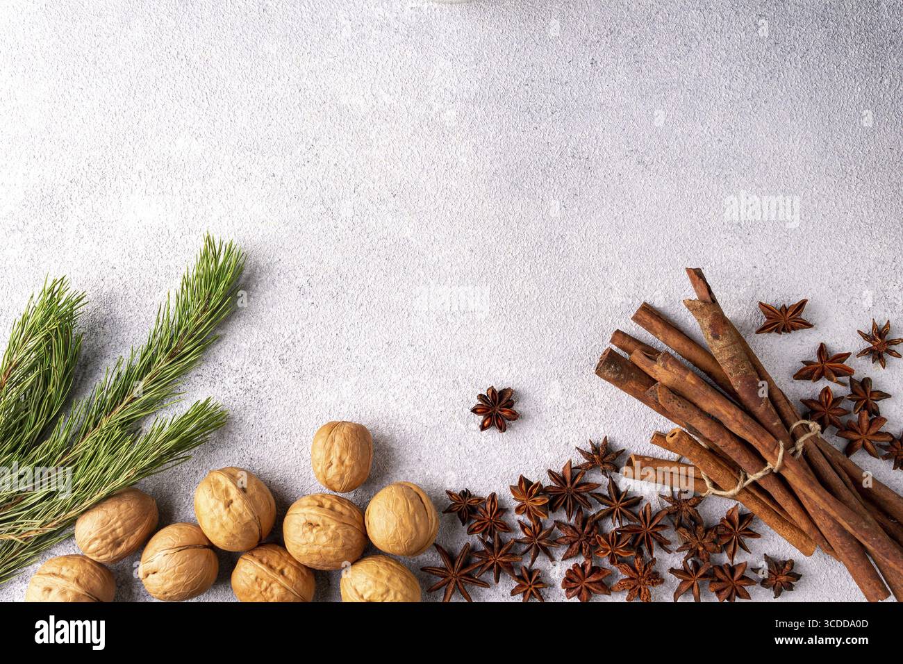 Bastoncini di cannella, anice stellato e rami di pino si trovano su intonaco grigio Foto Stock