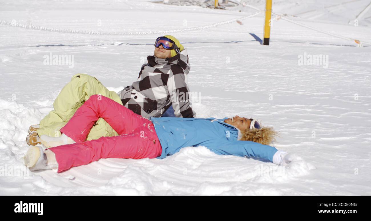 Giovane uomo e donna in abiti da sci che si rilassano per riposare sulla neve in montagna dopo una giornata intensa sulla pista Foto Stock