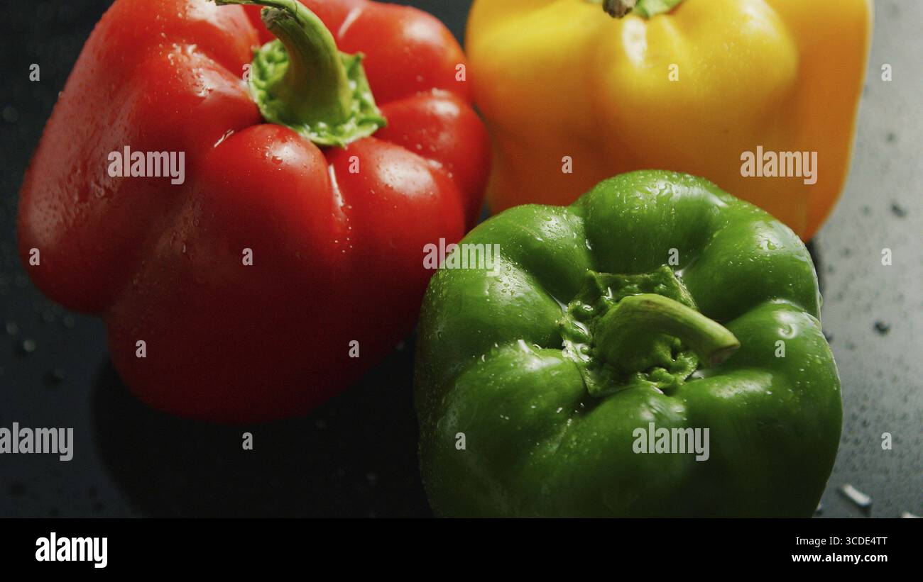 Primo piano della shiny peperoni di colori diversi con superficie bagnata in acqua scende Foto Stock