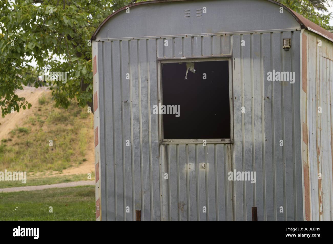 La struttura in metallo fatiscente con finestra rotta in un parco simboleggia il decadimento urbano e l'abbandono Foto Stock