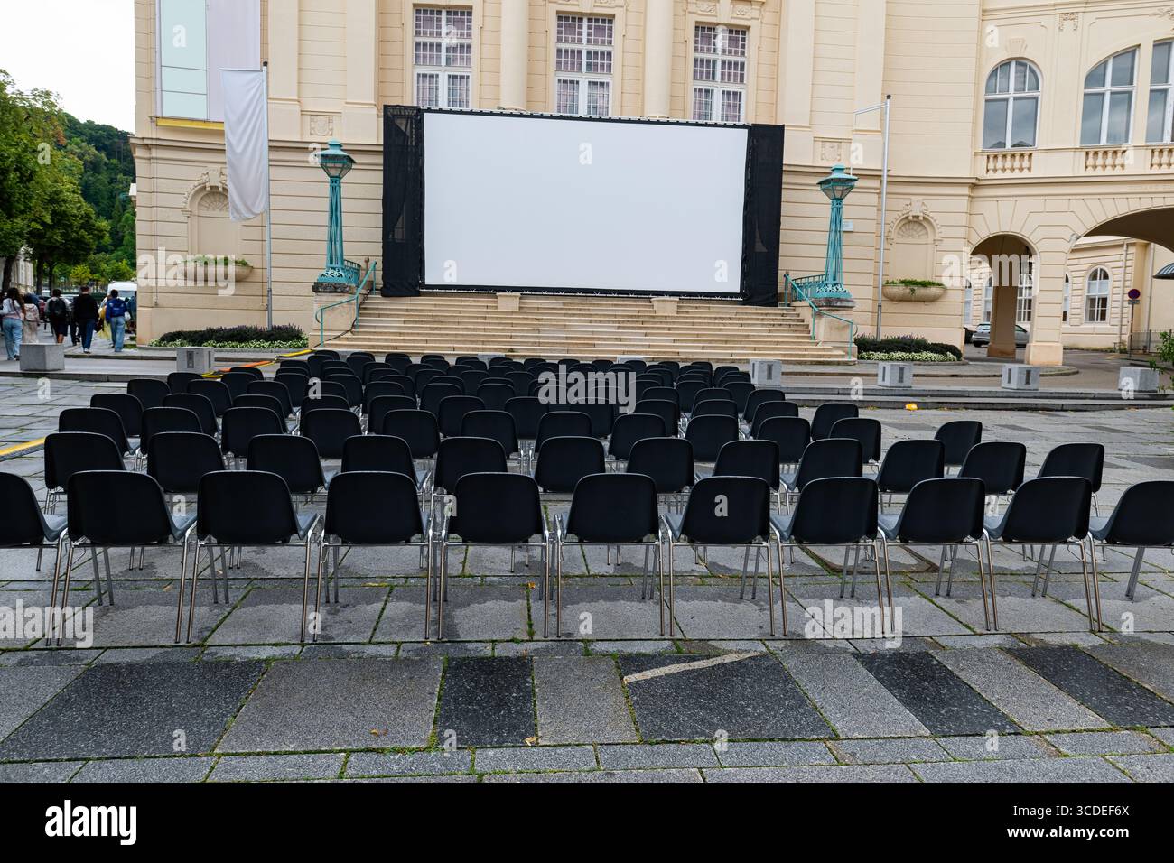 Il cinema all'aperto allestito di fronte all'edificio storico riflette il silenzio pre-spettacolo con i suoi posti vuoti. Foto Stock