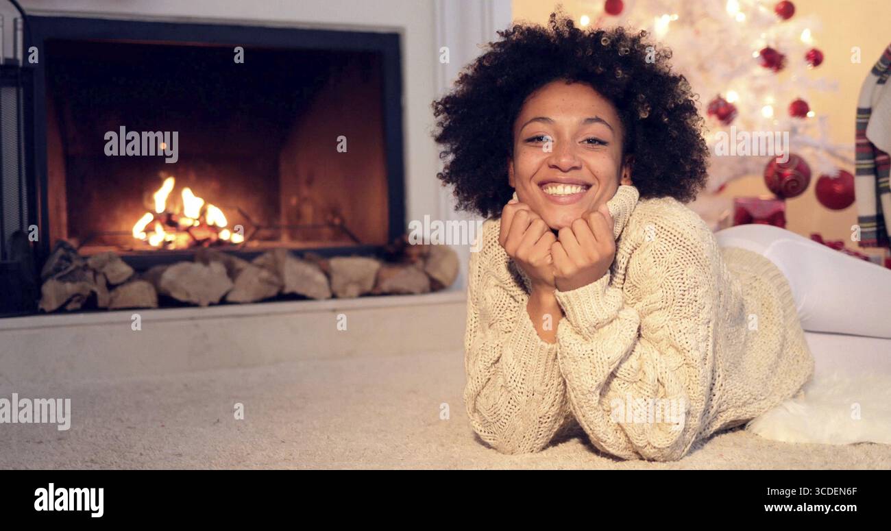 Donna di camino e indossa un maglione pesante sorrisi a telecamera mentre in bilico su un tappeto Foto Stock