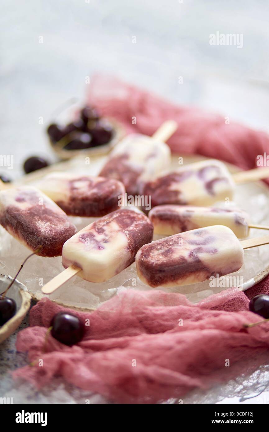 Papaveri vegani alla ciliegia fatti in casa con latte di cocco. Posizionato su una piastra in ceramica. Concetto gastronomico estivo. Disposizione piatta, vista dall'alto Foto Stock