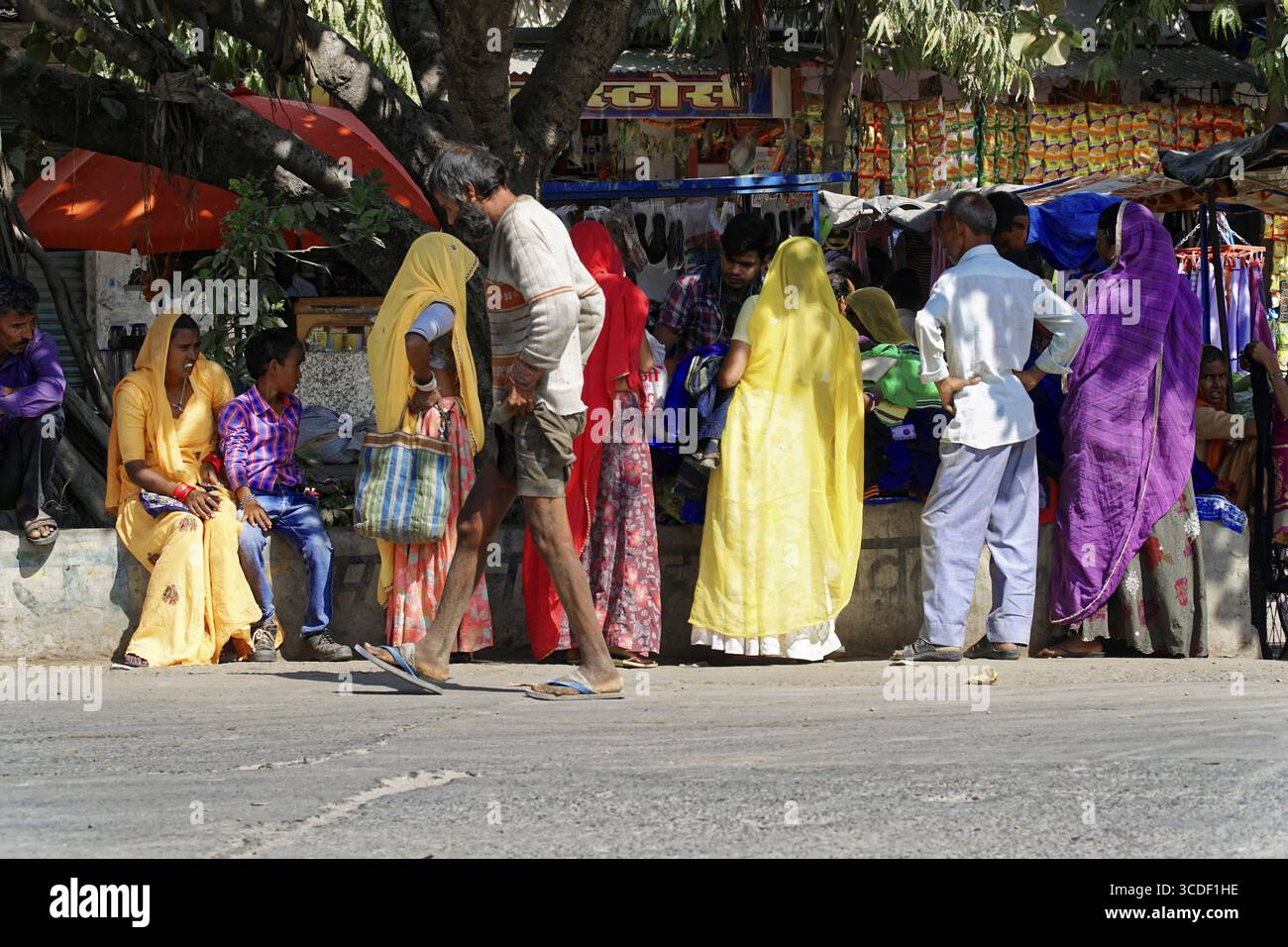 Nei pressi di Jodhpur, Rajasthan, India del Nord, Asia, persone in vesti colorate si riuniscono all'ombra sulla strada, Jodhpur, Ranapur Foto Stock