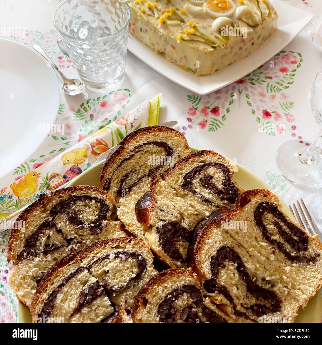 Cozonac, dolce tradizionale rumeno di Pasqua o di Natale. Tagliare il pane dolce su un piatto e l'insalata russa sullo sfondo. Direttamente sopra. Foto Stock