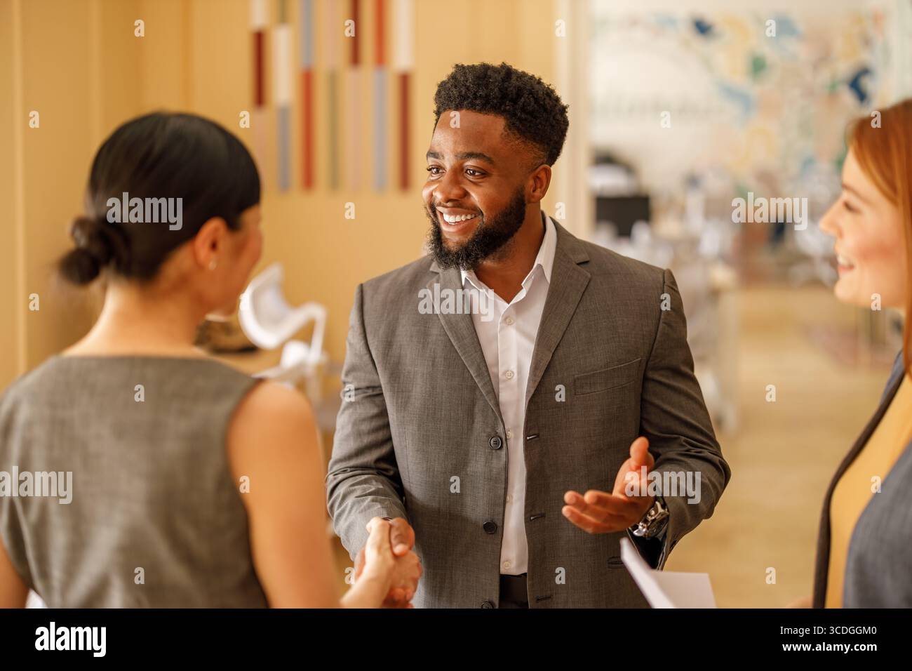 Un uomo d'affari felice che dà una stretta di mano alle donne professioniste dopo una discussione di successo sul progetto in ufficio Foto Stock