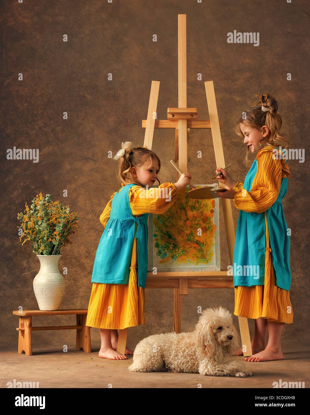 Due bambine e sorelle dipingono i fiori di mimosa su un cavalletto con delle pitture. Pittura, infanzia, felicità Foto Stock