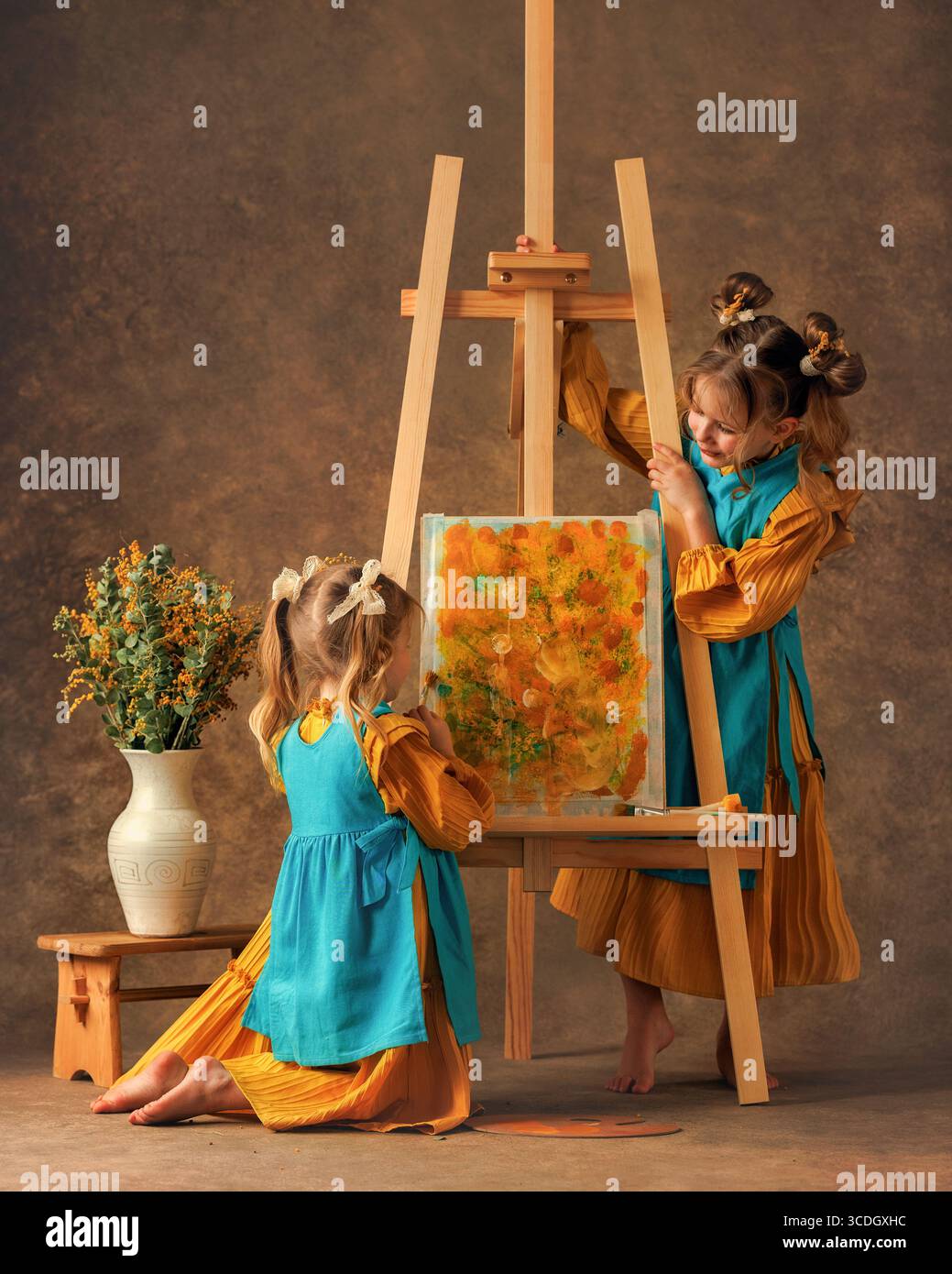 Due bambine e sorelle dipingono i fiori di mimosa su un cavalletto con delle pitture. Pittura, infanzia, felicità Foto Stock