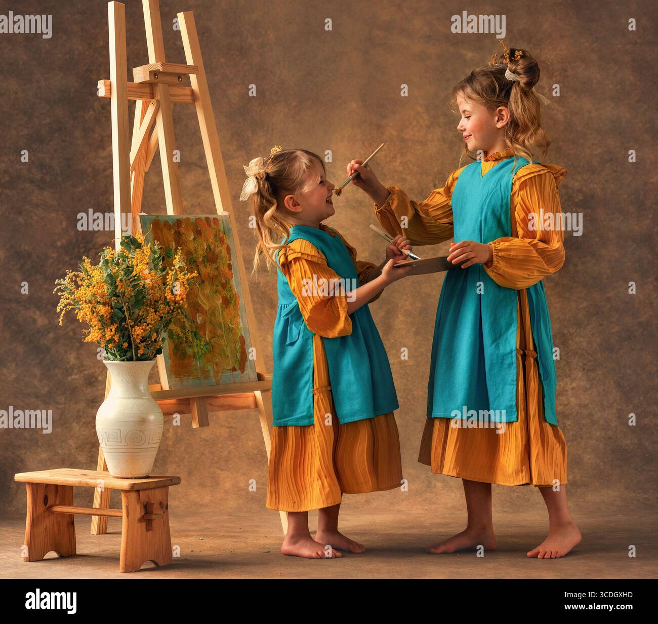 Due bambine e sorelle dipingono i fiori di mimosa su un cavalletto con delle pitture. Pittura, infanzia, felicità Foto Stock