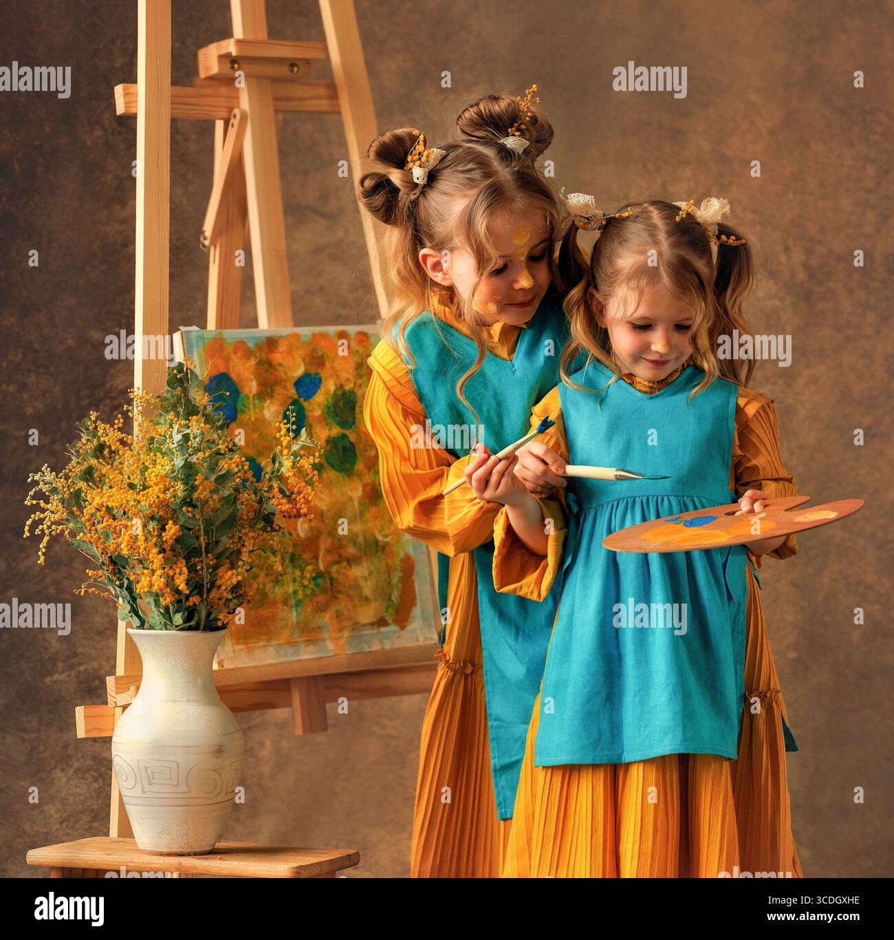 Due bambine e sorelle dipingono i fiori di mimosa su un cavalletto con delle pitture. Pittura, infanzia, felicità Foto Stock