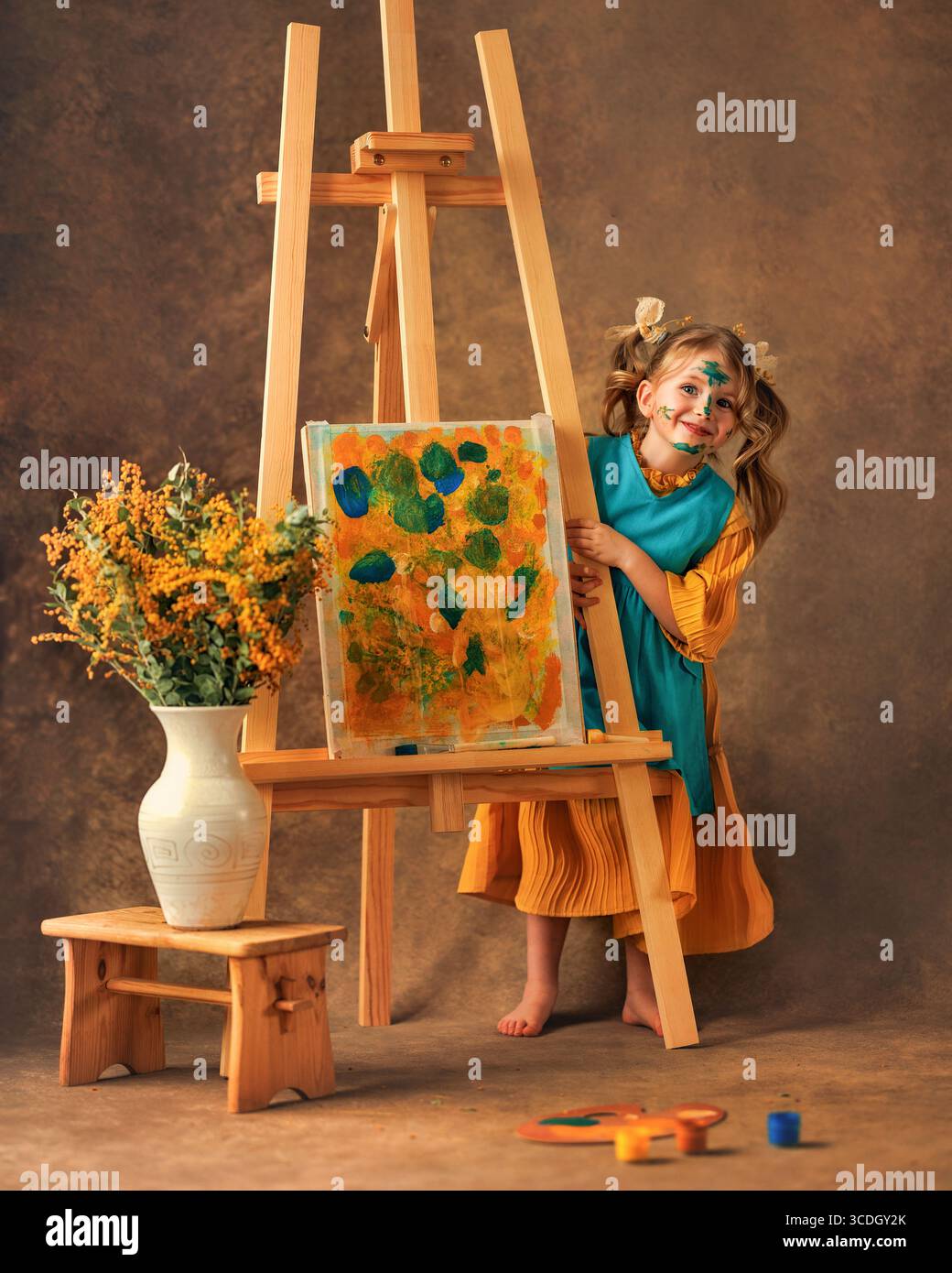 La bambina dipinge i fiori mimosa su un cavalletto con delle vernici. Pittura, infanzia, felicità, ragazzo Foto Stock