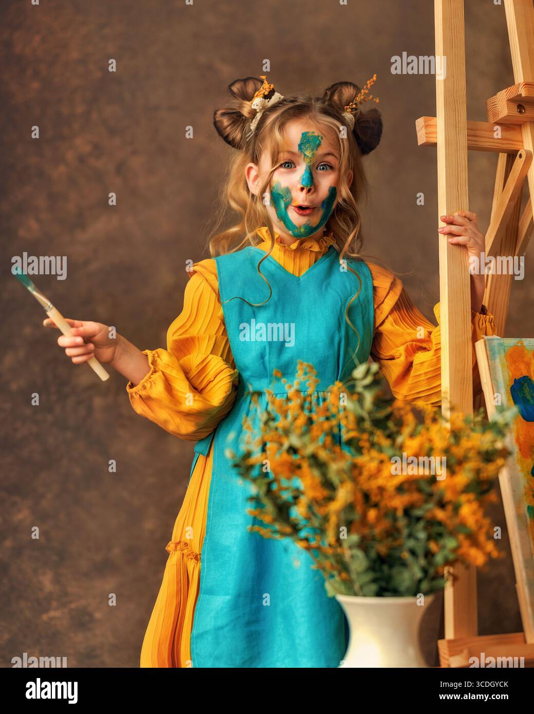 La bambina dipinge i fiori mimosa su un cavalletto con delle vernici. Pittura, infanzia, felicità, ragazzo Foto Stock