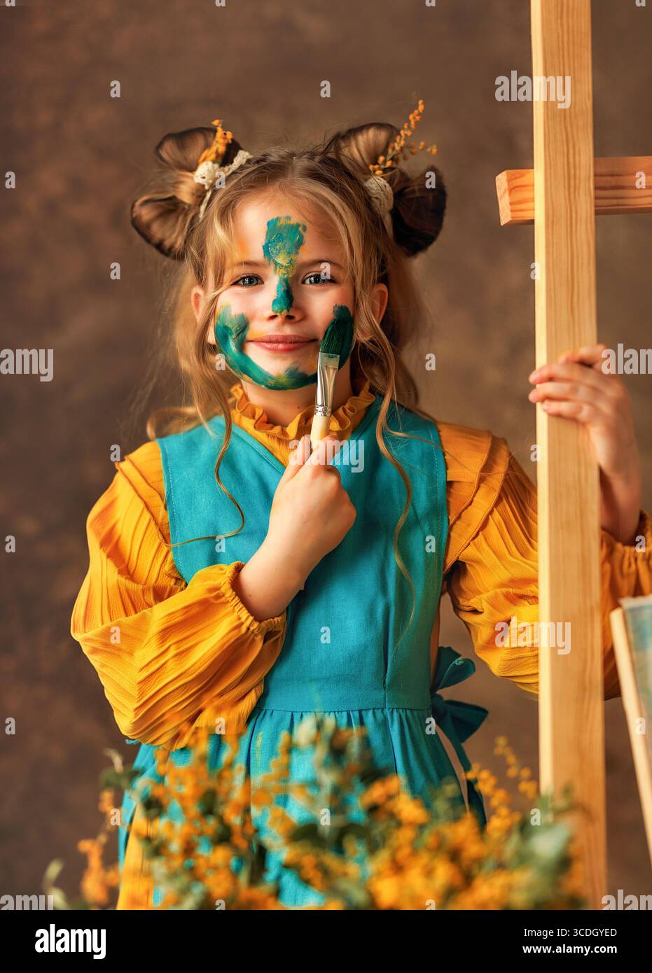 La bambina dipinge i fiori mimosa su un cavalletto con delle vernici. Pittura, infanzia, felicità, ragazzo Foto Stock