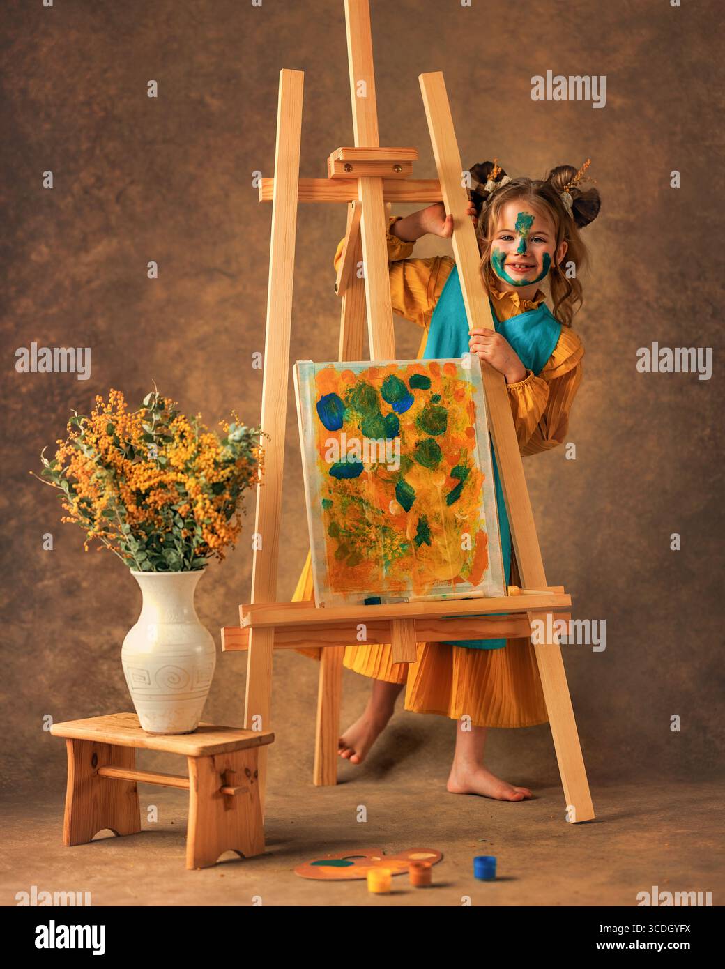 La bambina dipinge i fiori mimosa su un cavalletto con delle vernici. Pittura, infanzia, felicità, ragazzo Foto Stock