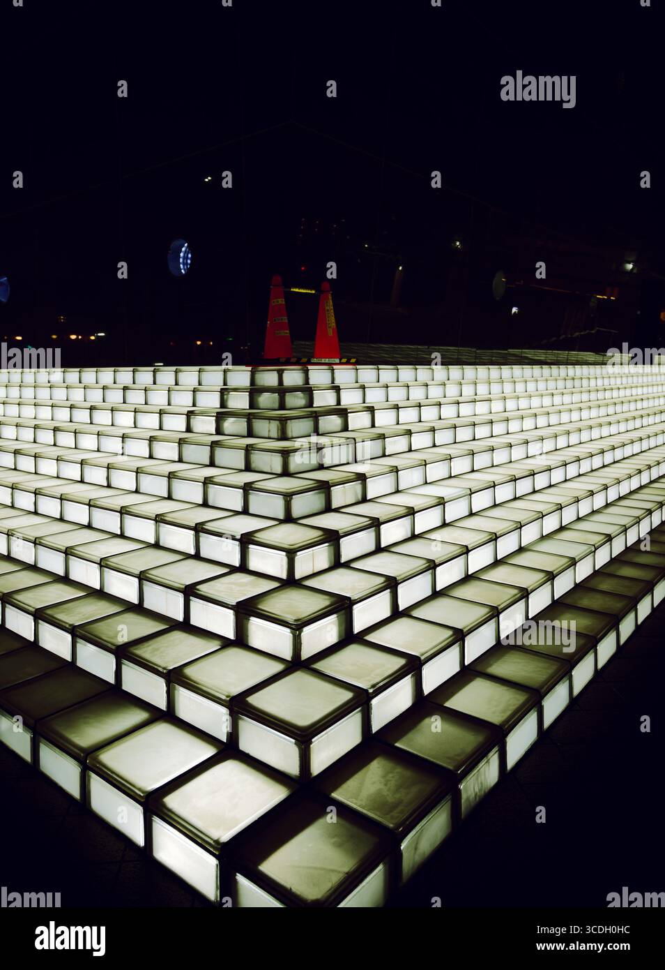 Scala in vetro illuminata illuminata di notte a Sumida City, con due coni di avvertenza arancioni posizionati in alto. Foto Stock