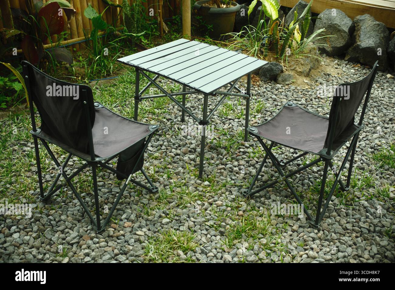 Tavolo da campeggio pieghevole all'aperto con sedie su un patio con ghiaia Foto Stock