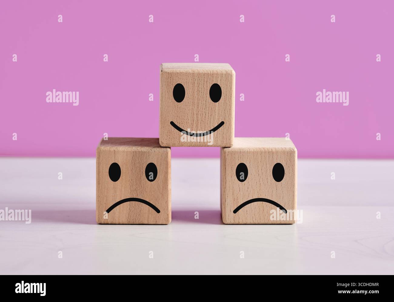 Concetto di feedback positivo e negativo con cubi di legno e volti emoticon che rappresentano consapevolezza, felicità, soddisfazione del cliente o insoddisfazione Foto Stock