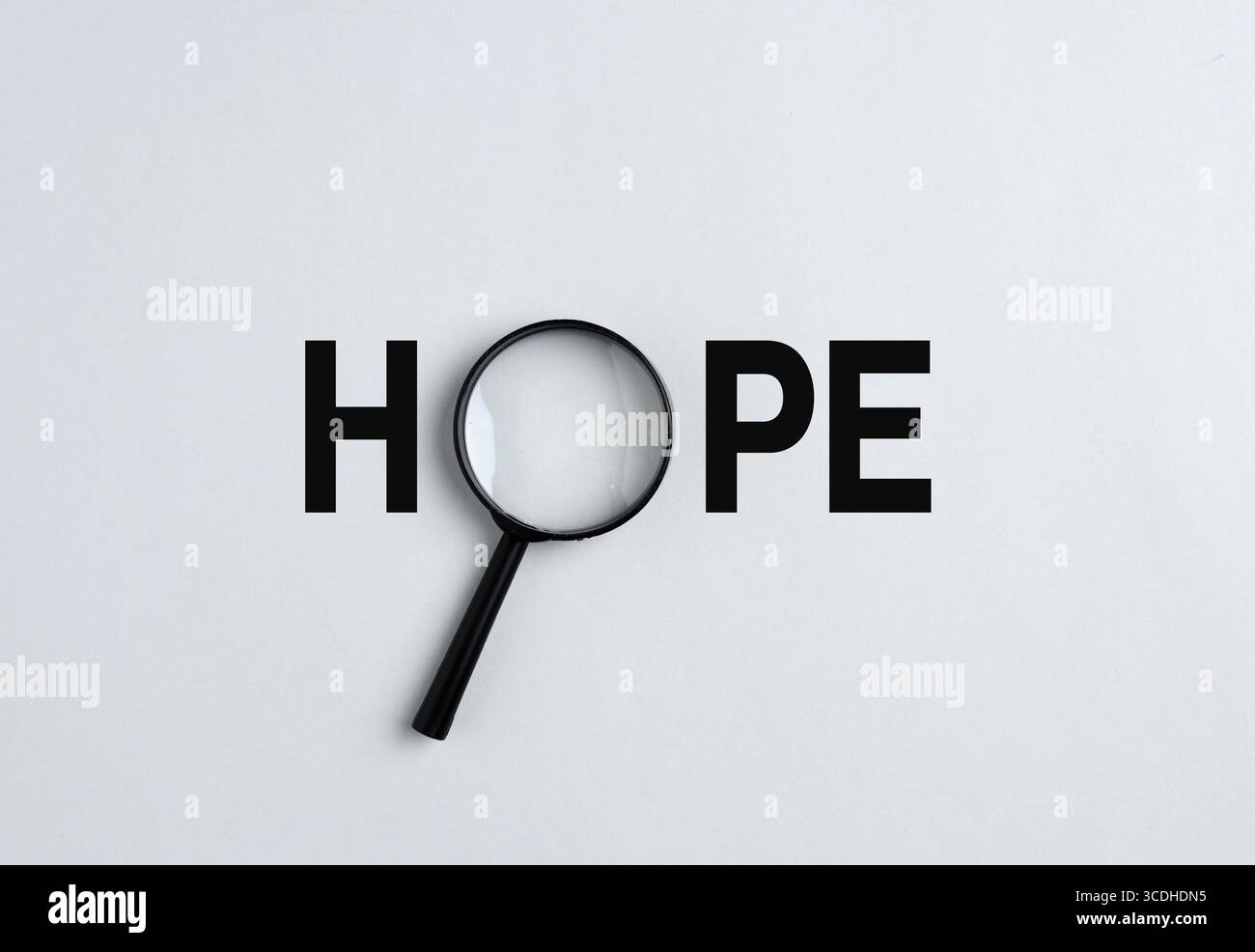 La lente d'ingrandimento sta esplorando la parola speranza, simboleggiando la ricerca di positività e aspettativa in futuro. Alla ricerca di un concetto di speranza. Foto Stock