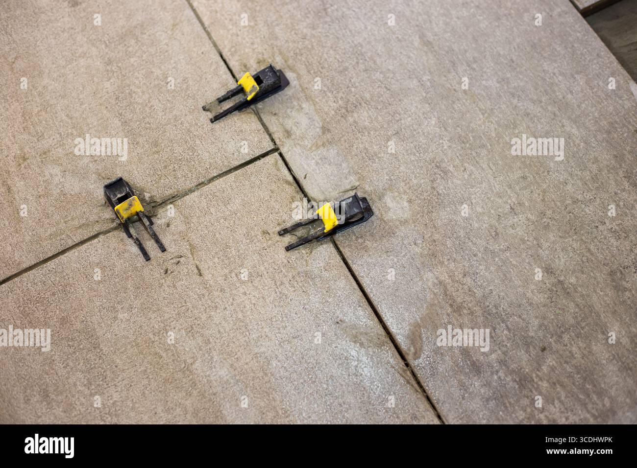 Le clip di livellamento per piastrelle sono installate tra le piastrelle del pavimento, garantendo una distanza uniforme tra le piastrelle e una superficie piana. Foto Stock