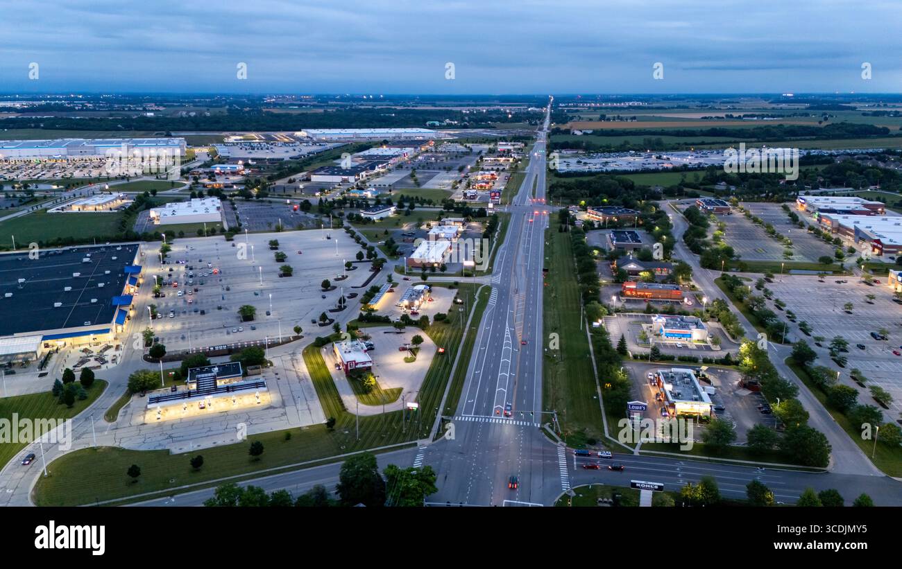 Una vista panoramica aerea al crepuscolo o all'alba cattura un vasto paesaggio suburbano con un'autostrada prominente che dissocia la scena Foto Stock