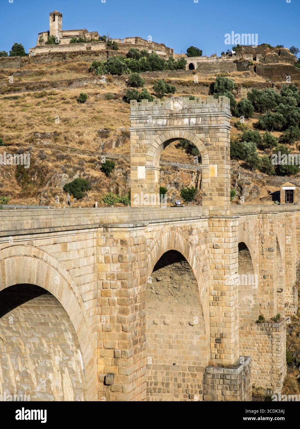 Il ponte romano di Alcántara mentre attraversa il fiume Tago, con il Convento di Las Comendadoras sullo sfondo. Foto Stock